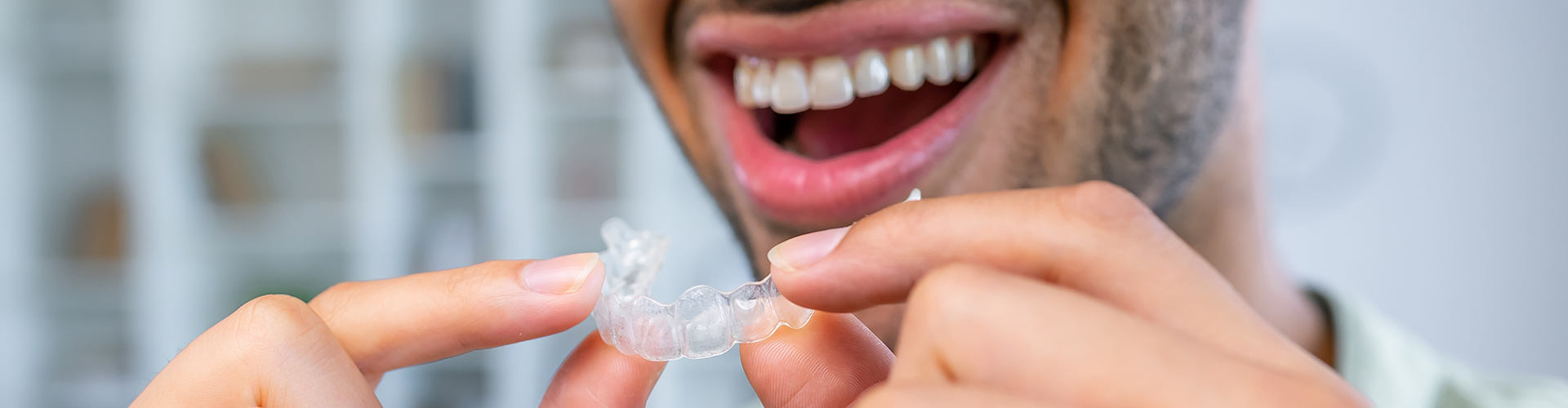 smiling man holding clear aligner