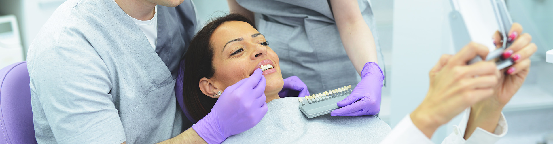 dental staff holding tooth shade-matching tool with patient