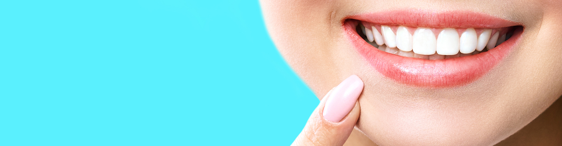 Close-up of a woman pointing to her smile.