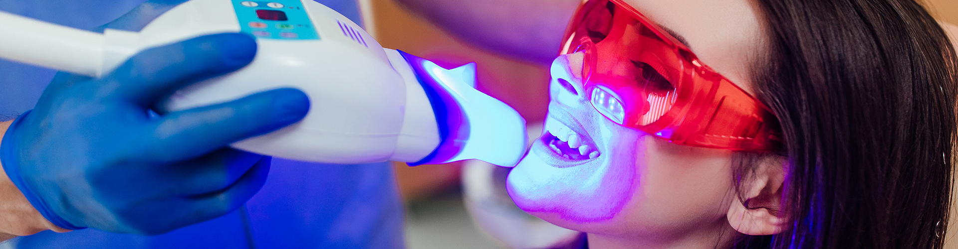 dentist shining led light on patient's teeth