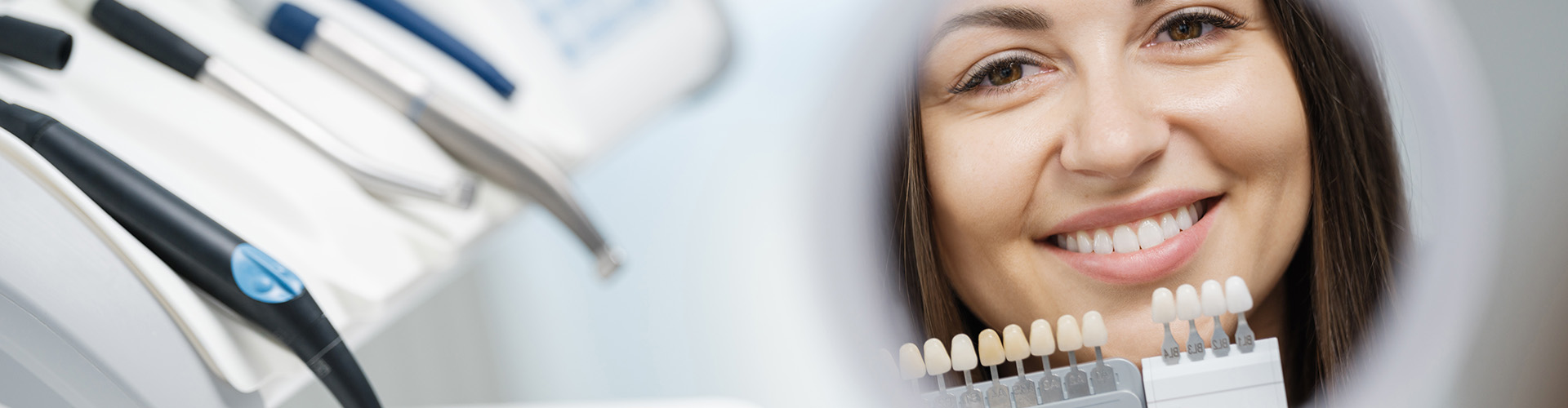 woman smiling into mirror with shade-matching tool