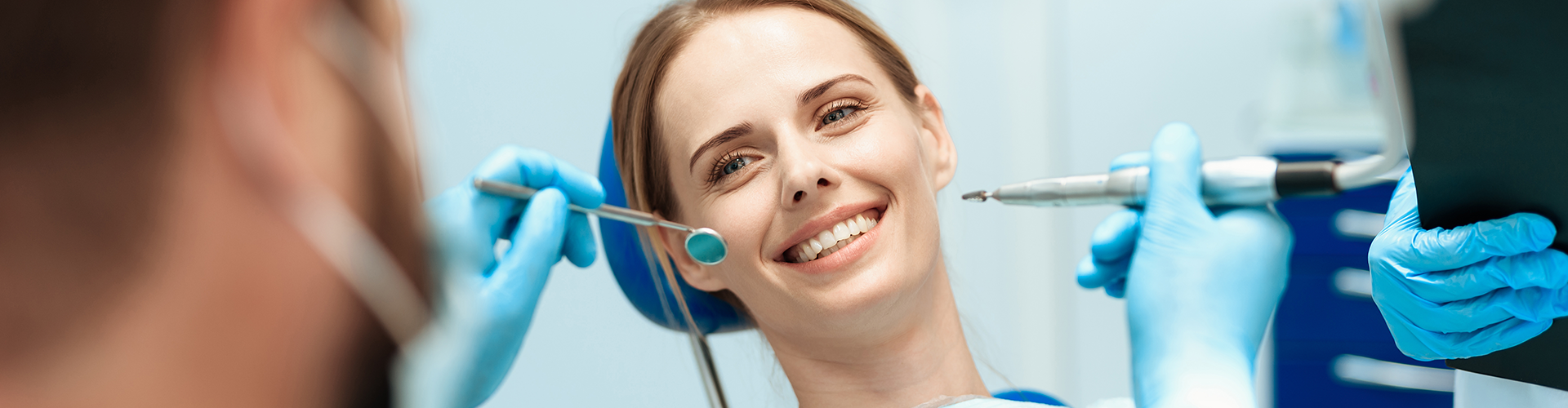 dentist holding dental tools in front of smiling woman in dental chair