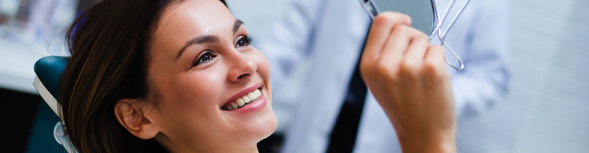 A woman smiling while holding a mirror.