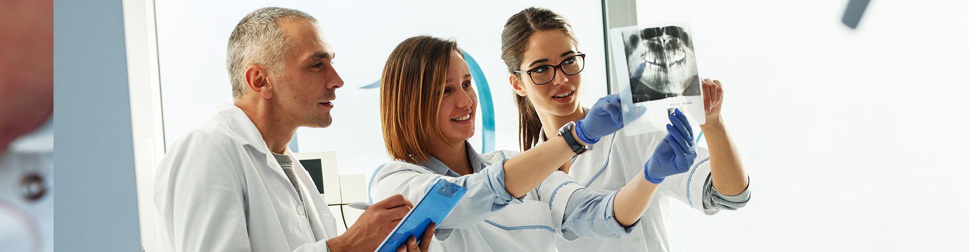 Three doctor reviewing dental x-rays.